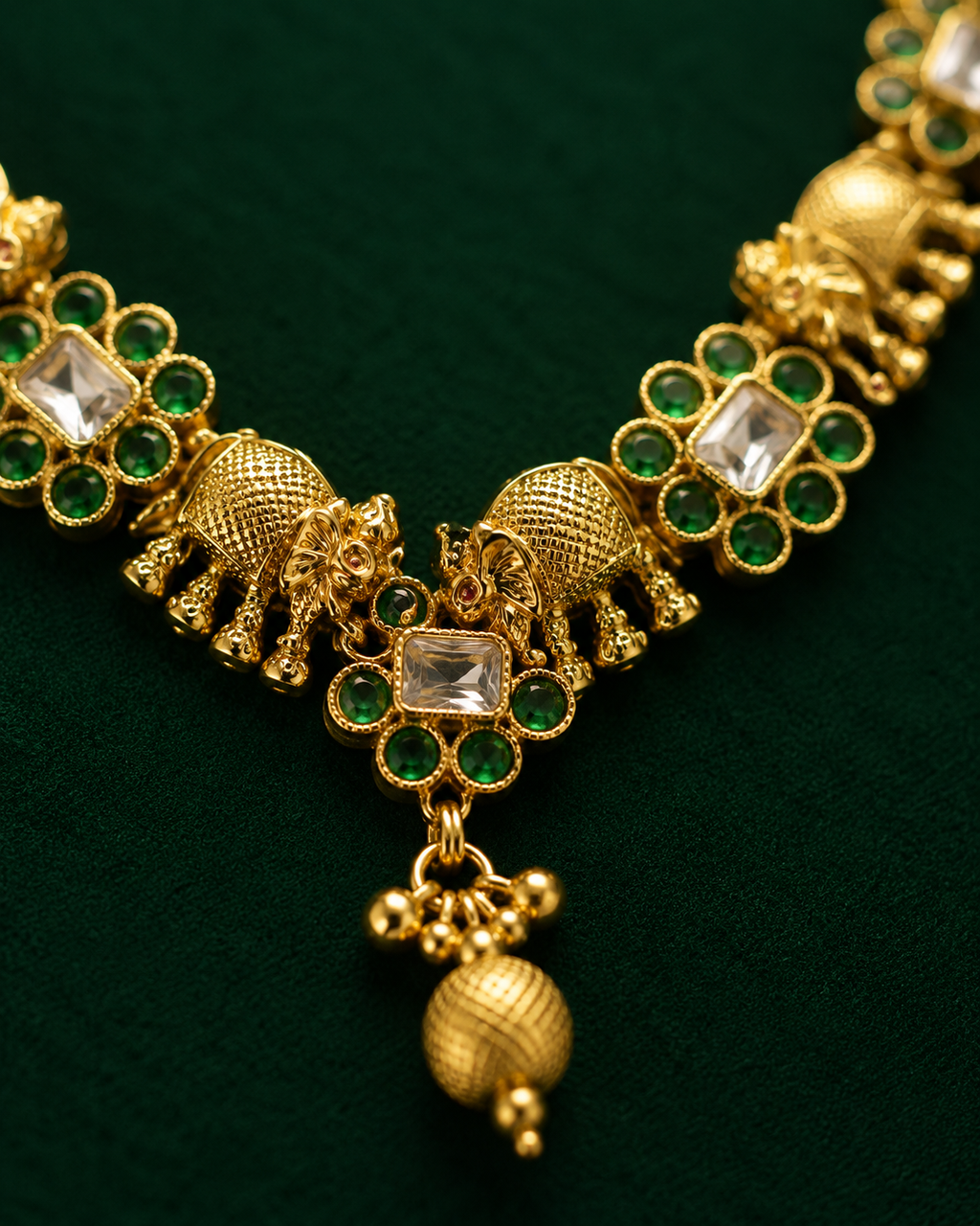 Close-up of elephant motif kundan necklace centre piece with green stones and gold bead drop