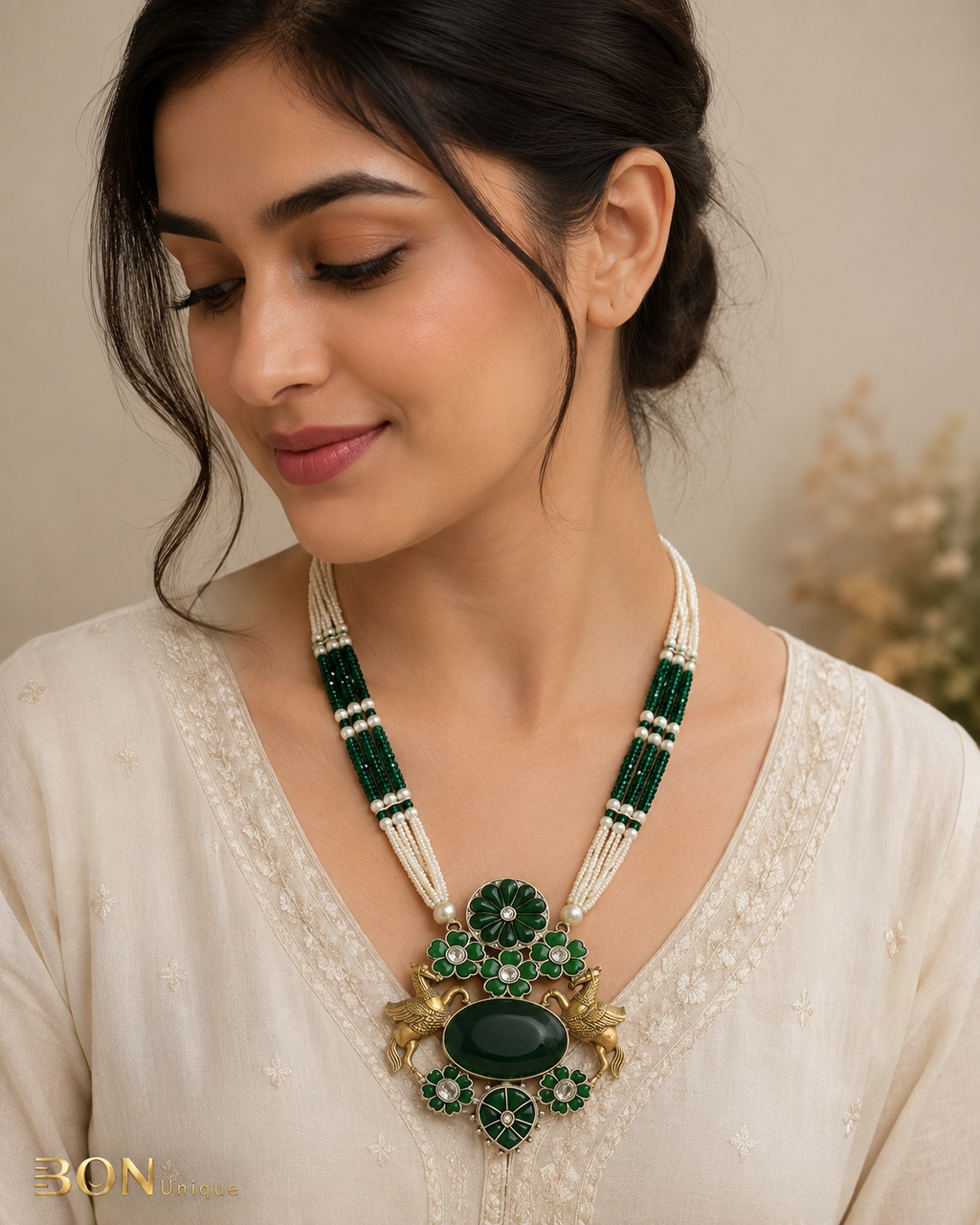 Model wearing antique gold dual Pegasus necklace with green enamel and emerald cabochon on ivory kurta
