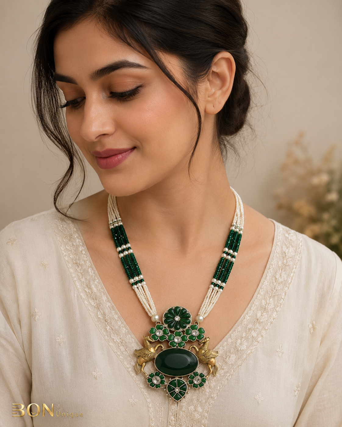 Model wearing antique gold dual Pegasus necklace with green enamel and emerald cabochon on ivory kurta