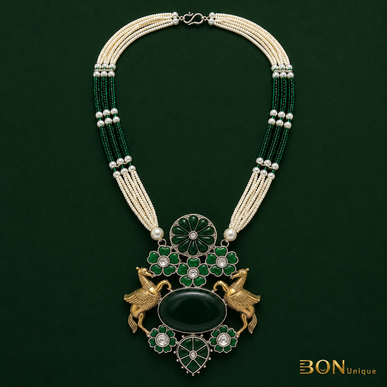 Full view of antique gold dual Pegasus necklace with multi-strand green bead and pearl chain on dark green background