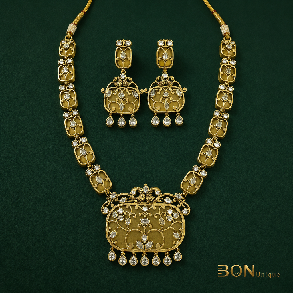 Full set view of antique gold peacock kundan long necklace with chandelier earrings on dark green background
