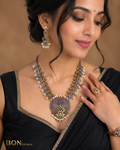 Model wearing dual-tone peacock necklace set with ruby stones and pearl drops on black saree
