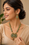 Model wearing antique gold elephant necklace set with green enamel and polki stones on beige saree