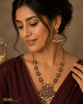 Model wearing antique gold dual deer necklace set with mauve enamel and pearl drops on maroon saree